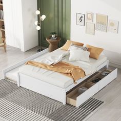 a white bed with two drawers underneath it in a room next to a green door