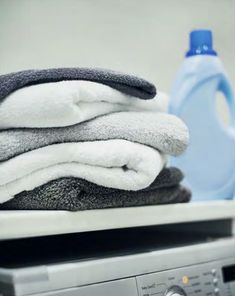 stack of towels on top of washing machine with bottle of water in the back ground