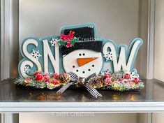 a snowman is sitting on top of a shelf in front of a sign that says snow