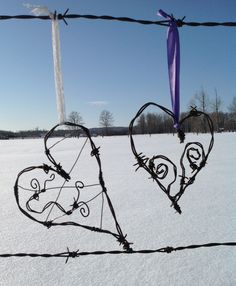 two hearts are attached to a barbed wire fence in the middle of a snow covered field