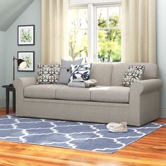 a living room scene with focus on the couch and pillows in front of the window