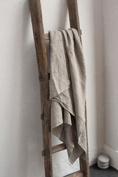 an old wooden ladder leaning against a wall with a towel hanging from it's side