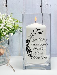 a white candle sitting next to a vase filled with flowers