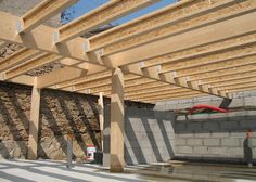 the inside of a building being built with wooden beams and concrete blocks on the ground