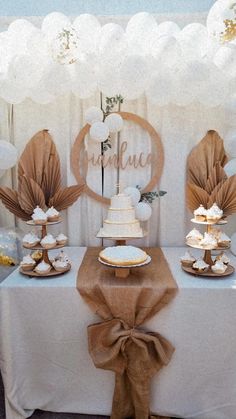 a table topped with cake and desserts on top of white tables clothed in brown