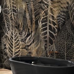 a bath tub sitting next to a wall covered in leafy designs on it's side