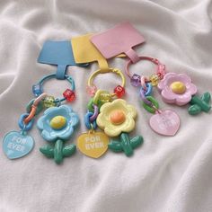 several colorful plastic key chains laying on top of a white sheet with letters and flowers