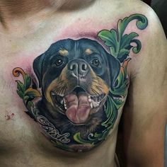 a man's chest with a tattoo of a dog on it and leaves around his neck