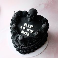 a heart shaped cake decorated with skulls and writing rip to my 20's on a plate