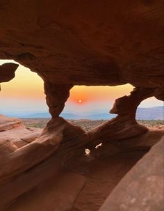 the sun is setting in between two large rocks