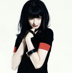 a woman with black hair wearing a red and black shirt is posing for the camera