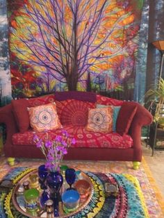 a living room with a red couch and colorful rugs on the floor next to a tree