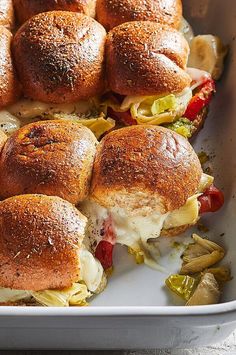 a pan filled with sliders covered in cheese and toppings, sitting on a table