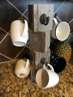 a birdhouse made out of wood with cups on the top and two mugs hanging from it's sides