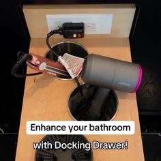 a hair dryer sitting on top of a wooden table next to a pot filled with items