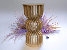 two wooden vases sitting next to each other on top of a white table with purple flowers