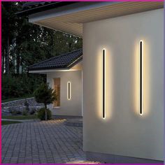 three lights are lit up on the side of a white wall in front of a house