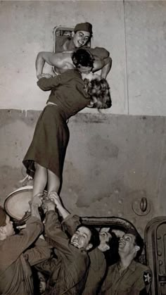 an old black and white photo of a woman on top of a man in the air