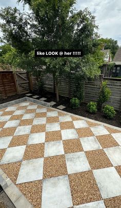 a large checkerboard pattern in the middle of a yard with trees and bushes