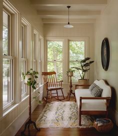 a living room filled with furniture and lots of windows next to a wooden rocking chair