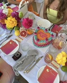 a table topped with plates and cake next to flowers on top of a white table cloth