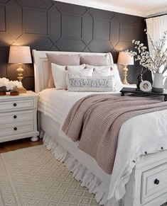 a white bed sitting in a bedroom on top of a wooden floor next to two lamps