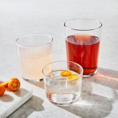 two glasses filled with liquid next to an orange