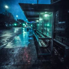 a bus stop sitting on the side of a road at night