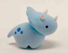 a small blue toy animal with horns on it's head and tail, sitting in front of a white background