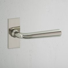 a close up of a door handle on a white wall with a light gray background