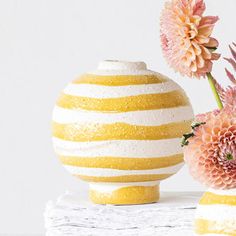 two vases with flowers in them sitting on a table next to each other, one yellow and the other white