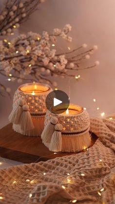 two candles with tassels sitting on top of a table