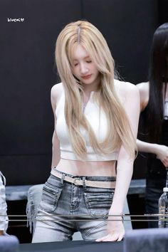 a woman with long hair standing in front of a table