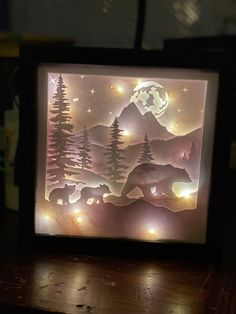 a lit up box with an image of bears in the woods and trees on it