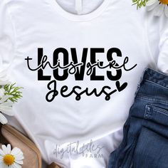 a t - shirt with the words love is jesus on it next to daisies