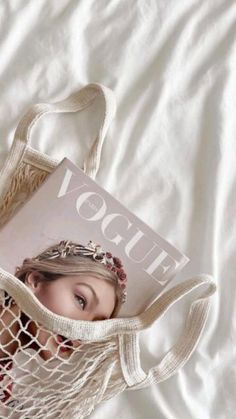 a woman laying in bed with a book inside of her netted tote bag