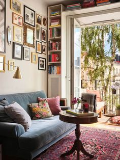 a living room filled with furniture and lots of pictures on the wall next to a window