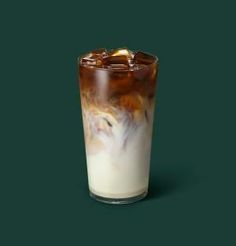 a tall glass filled with ice cream and liquid on a dark green background, topped with an orange slice