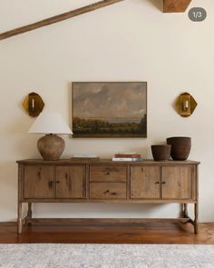 a wooden table with two vases on it and a painting hanging above the table