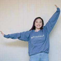 a woman in a blue shirt is standing with her arms outstretched and smiling at the camera