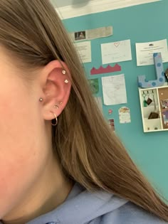 a girl with ear piercings in front of a bulletin board