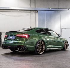 the rear end of a green car parked in a garage