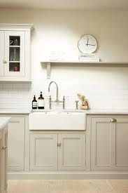 a kitchen with white cabinets and a clock on the wall above the sink is shown