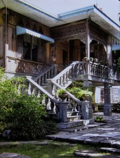 an old house with stone steps leading up to the front door and second story balcony