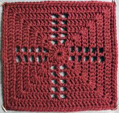 a red crocheted square with holes in the middle