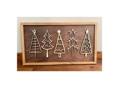 wooden christmas tree cutouts in a frame on top of a table next to a wall