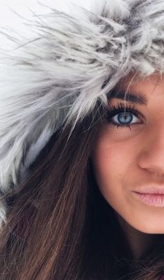 a woman with blue eyes wearing a furry hat