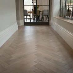 an empty room with wood flooring and glass door leading into the dining room area