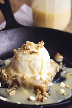 an ice cream sundae in a skillet with nuts on the rim and toppings