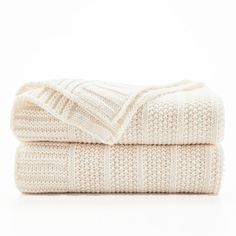 two white knitted blankets folded on top of each other in front of a white background